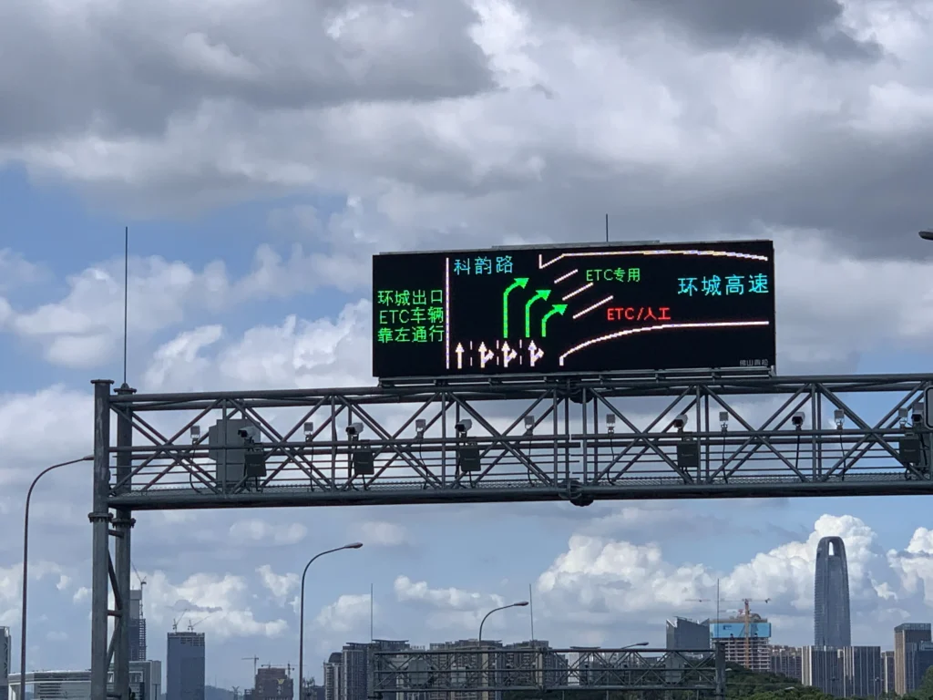 Outdoor full-color LED display mounted on a highway gantry, providing real-time traffic information and warnings