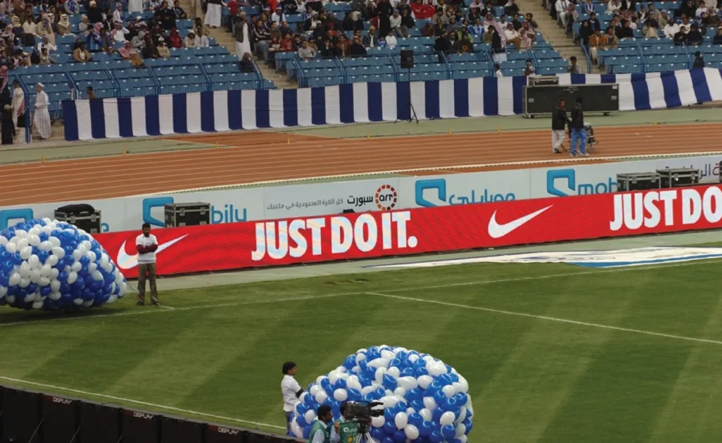 LED perimeter screens surrounding a soccer field, displaying vibrant advertisements and match information